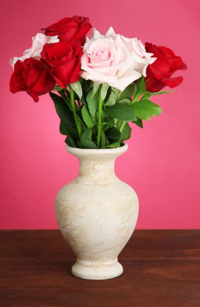 ピンクの背景にテーブルの上の贈り物と花瓶のバラの美しい花束 — ストック写真