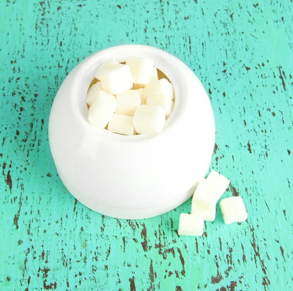 Azúcar refinado en un tazón de azúcar blanco sobre fondo de madera — Foto de Stock