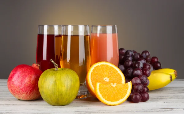 Glasses of fresh juice on table on gray background — Stock Photo, Image