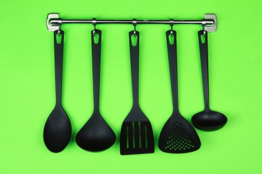 Gümüş kanca, yeşil arka plan üzerinde siyah mutfak gereçleri