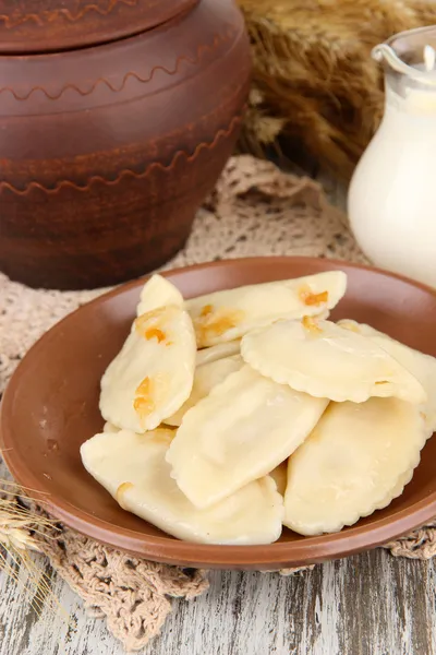 Tasty dumplings with fried onion on brown plate, on wooden background — Stock Photo, Image