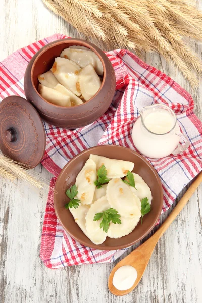Smakelijke dumplings met gebakken UI op bruin plaat, op houten achtergrond — Stockfoto
