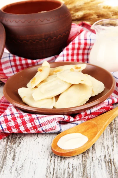 Smakelijke dumplings met gebakken UI op bruin plaat, op houten achtergrond — Stockfoto