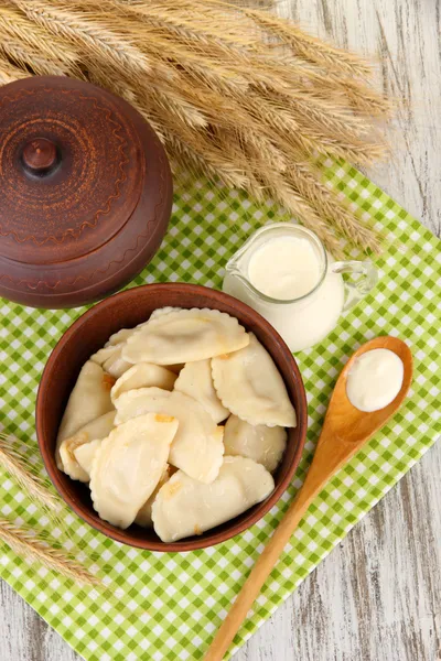 Tasty dumplings with fried onion on brown plate, on wooden background — Stock Photo, Image