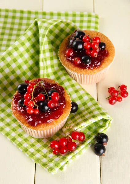 Smakelijke muffins met bessen op witte houten tafel — Stockfoto