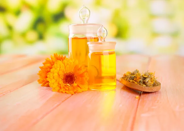 Medicine bottles and calendula flowers on wooden table — Stock Photo, Image