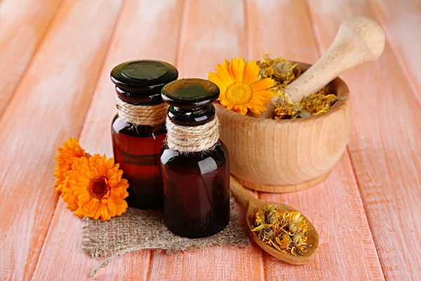 Frascos de medicina y flores de caléndula sobre fondo de madera — Foto de Stock