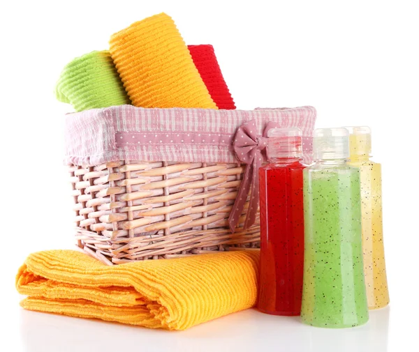 Colorful towels in basket and cosmetics bottles, isolated on white — Stock Photo, Image