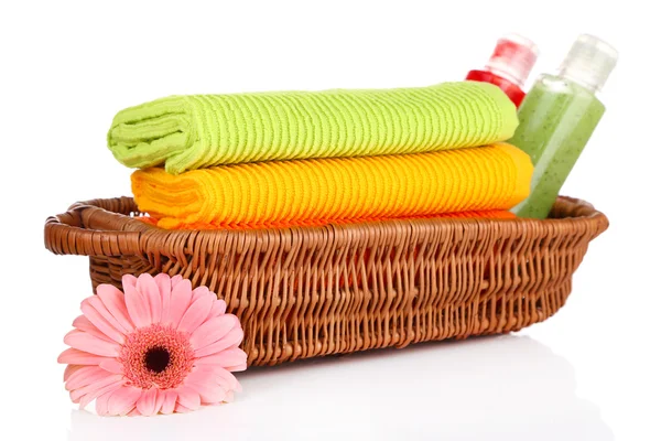 Colorful towels and cosmetics bottles in basket, isolated on white — Stock Photo, Image