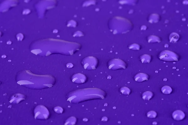 Gotas de agua sobre fondo plástico púrpura — Foto de Stock