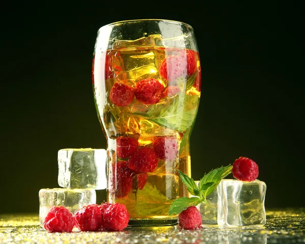 Iced tea with raspberries and mint on dark background with yellow light — Stock Photo, Image