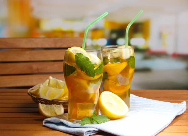 Té helado con limón y menta en la mesa de madera, al aire libre —  Fotos de Stock