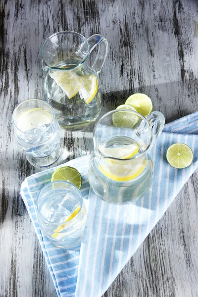 Glas kannor vatten och glasögon på träbord närbild — Stockfoto