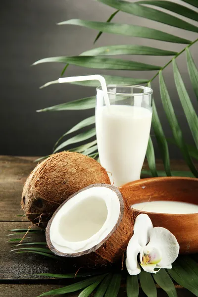 Coco con vaso de leche, sobre mesa de madera, sobre fondo gris —  Fotos de Stock