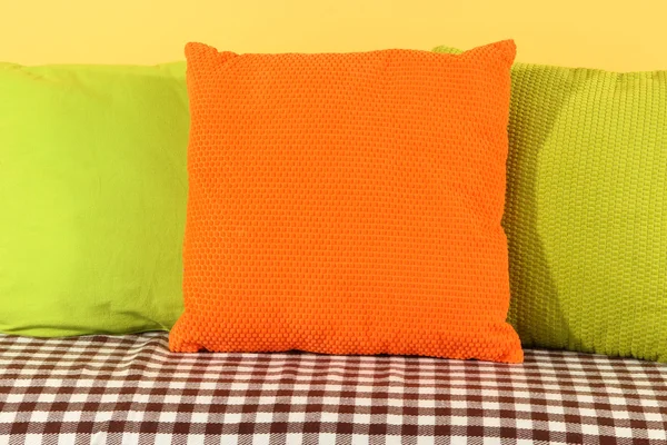 Travesseiros coloridos no sofá no fundo amarelo — Fotografia de Stock