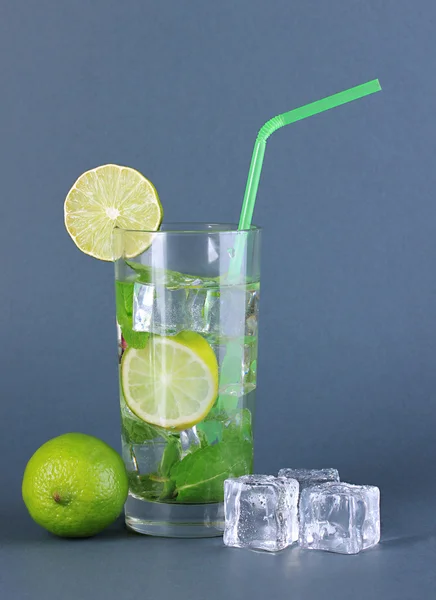 Bicchiere d'acqua con ghiaccio, menta e calce su fondo grigio — Foto Stock