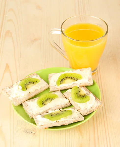 Sabrosos canapés con queso y kiwi, sobre plato de color, sobre fondo de madera — Foto de Stock