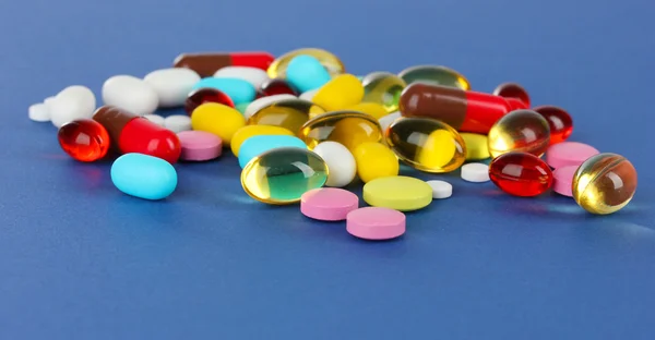 Assortment of pills, tablets and capsules on blue background — Stock Photo, Image