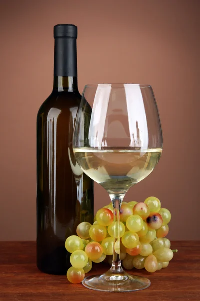 Composition of wine bottle, glass of white wine, grape on color background — Stock Photo, Image