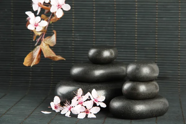 Piedras de spa y flores sobre fondo de bambú — Foto de Stock