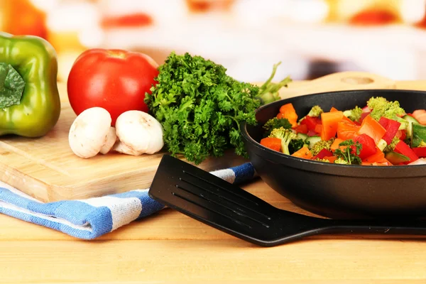 Ragú vegetal en sartén, sobre mesa de madera sobre fondo brillante — Foto de Stock