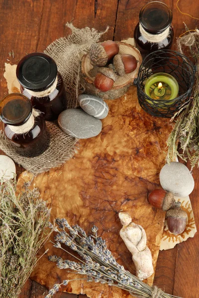 Composition with old papers, herbs, stones and bottles with symbols on wooden background — Stock Photo, Image