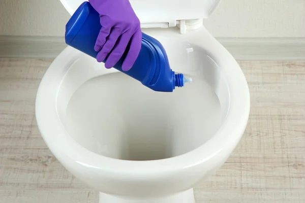 Woman hand with spray bottle cleaning a toilet bowl in a bathroom — Stock Photo, Image