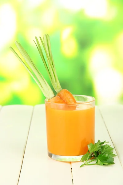Стекло морковного сока, на цветном деревянном столе на ярком фоне — стоковое фото