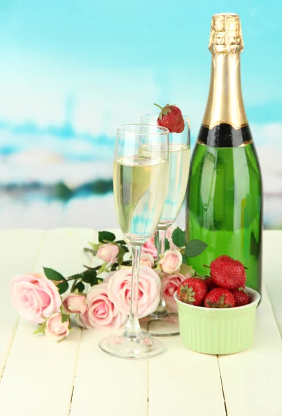 Романтичне натюрморт з шампанським, полуницею та рожевими трояндами на яскравому фоні — стокове фото