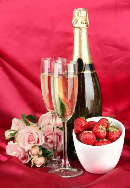 Romantic still life with champagne, strawberry and pink roses, on color fabric background — Stock fotografie