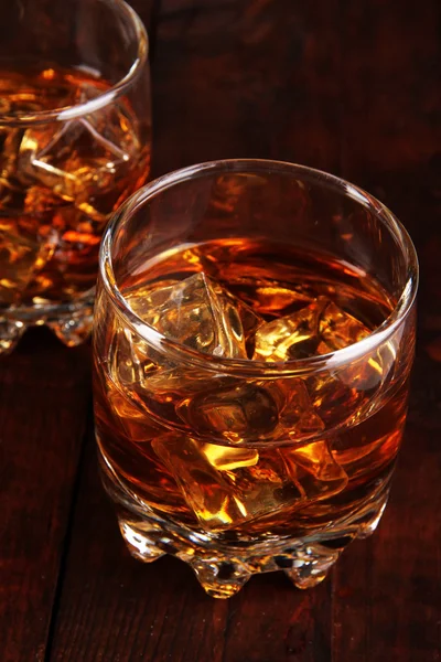 Brandy glasses with ice on wooden background — Stock Photo, Image