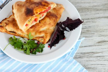 Pizza calzones tabakta üzerine peçete ahşap masa üzerinde