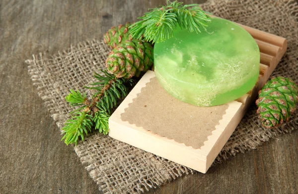 Handgemaakte zeep en groene dennenappels op houten achtergrond — Stockfoto