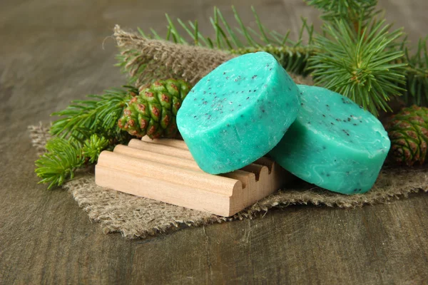 Hand-made soap and green pine cones on wooden background — Stock Photo, Image