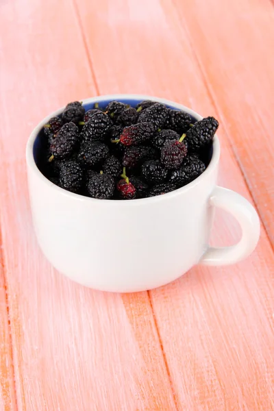 Moras maduras en taza sobre fondo de madera —  Fotos de Stock