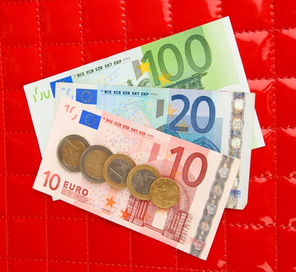 Euro banknotes and euro cents on red background — Stock Photo, Image