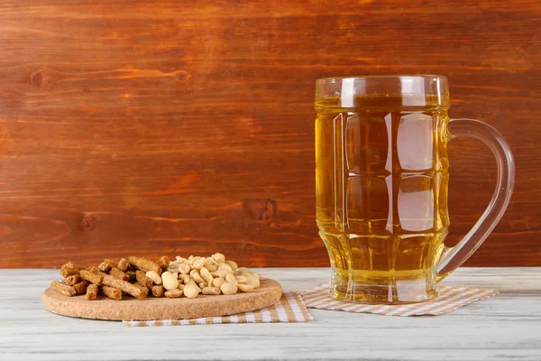 Birra in crocchette di vetro, e noci su tovagliolo sul tavolo su sfondo di legno — Foto Stock