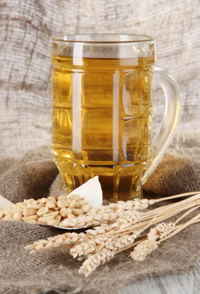 Cerveza en vaso y nueces en el ensacado sobre mesa de madera — Foto de Stock