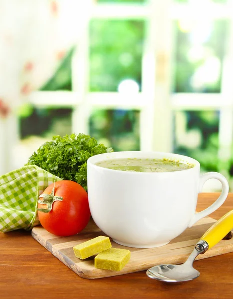 Coupe de soupe avec des cubes de bouillon sur table en bois — Photo