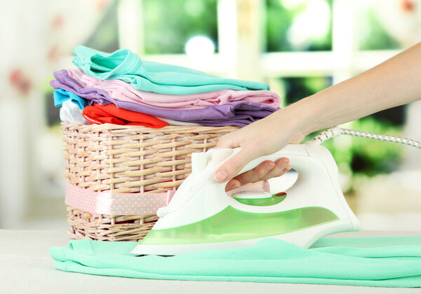 Рука женщины гладит одежду, на ярком фоне
