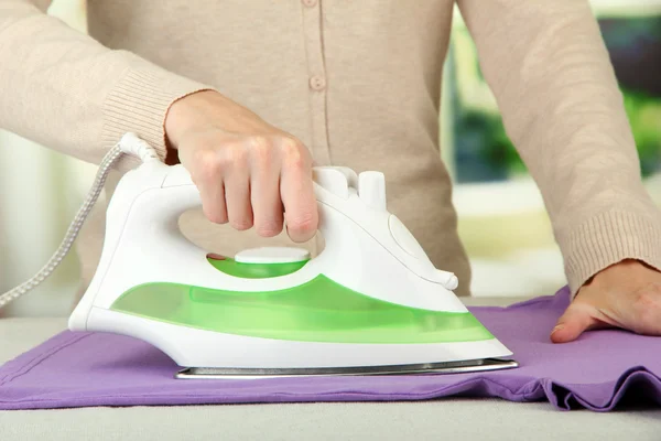 Woman's hand ironing clothes, on bright background — Stock Photo, Image