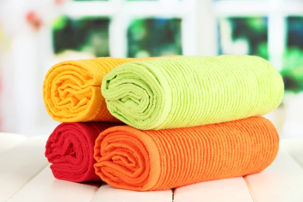 Colorful towels on wooden table on window background — Stock Photo, Image