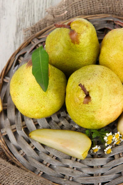 Pears on braided tray on burlap on wooden table — Zdjęcie stockowe