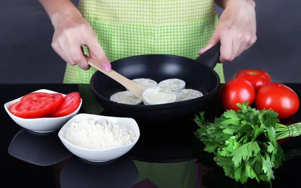 Τα χέρια μαγείρεμα κολοκυθάκια στο τηγάνι, σε γκρι φόντο — Φωτογραφία Αρχείου