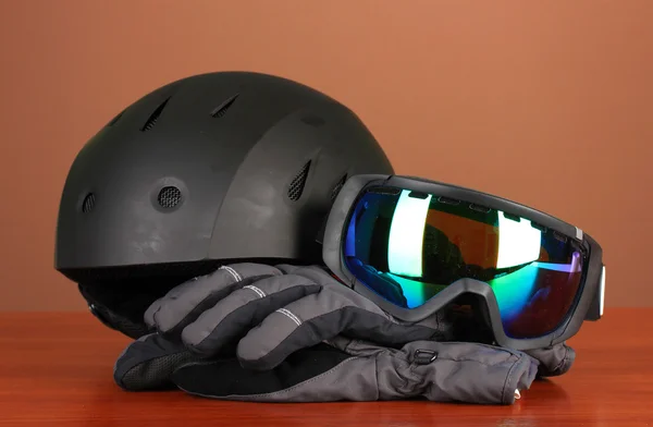 Okulary sportowe zimowe, kask i rękawice, na brązowym tle — Zdjęcie stockowe