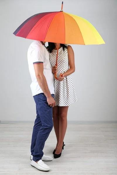 Beautiful loving couple with umbrella on grey background — Stock Photo, Image