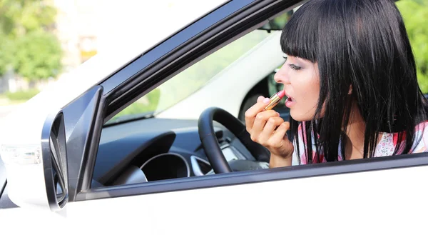 Mujer joven aplicando maquillaje en el coche — Foto de Stock