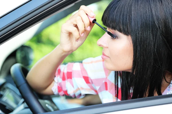 Mujer joven aplicando maquillaje en el coche —  Fotos de Stock