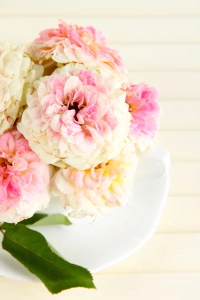 Roses in cup on wooden background — Stock Photo, Image