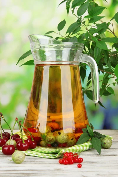 Pitcher of compote with summer berries on natural background — Stock Photo, Image